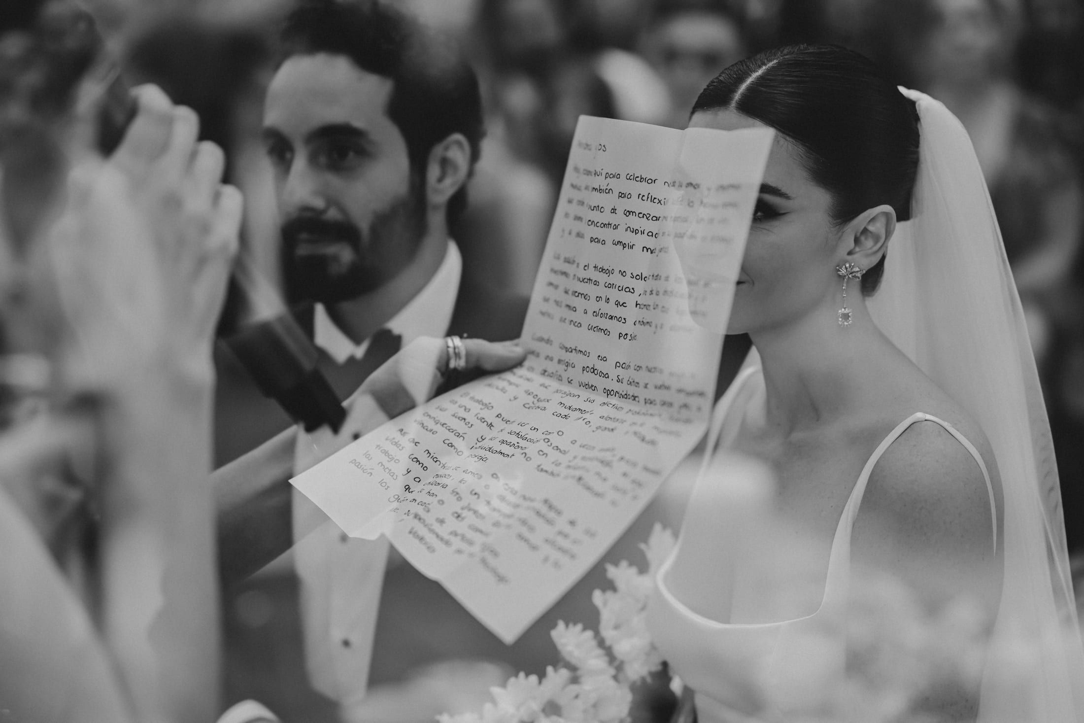 Primer plano de los novios en la ceremonia: él sostiene una carta escrita a mano, en blanco y negro