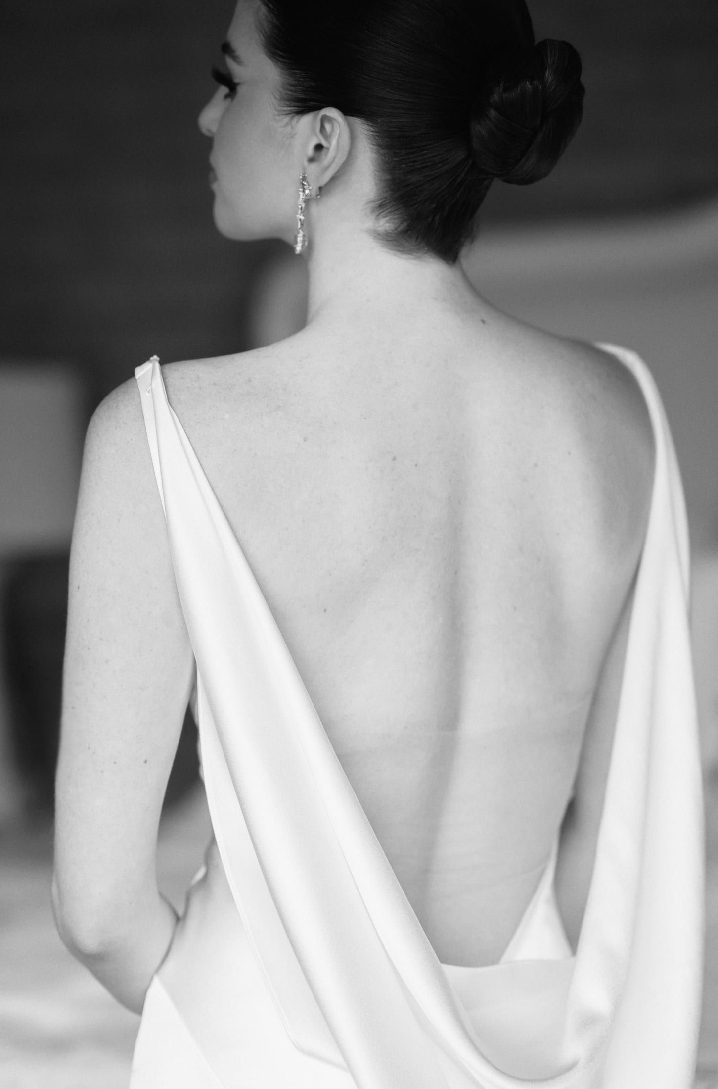 La novia de espaldas con vestido de espalda abierta, en blanco y negro
