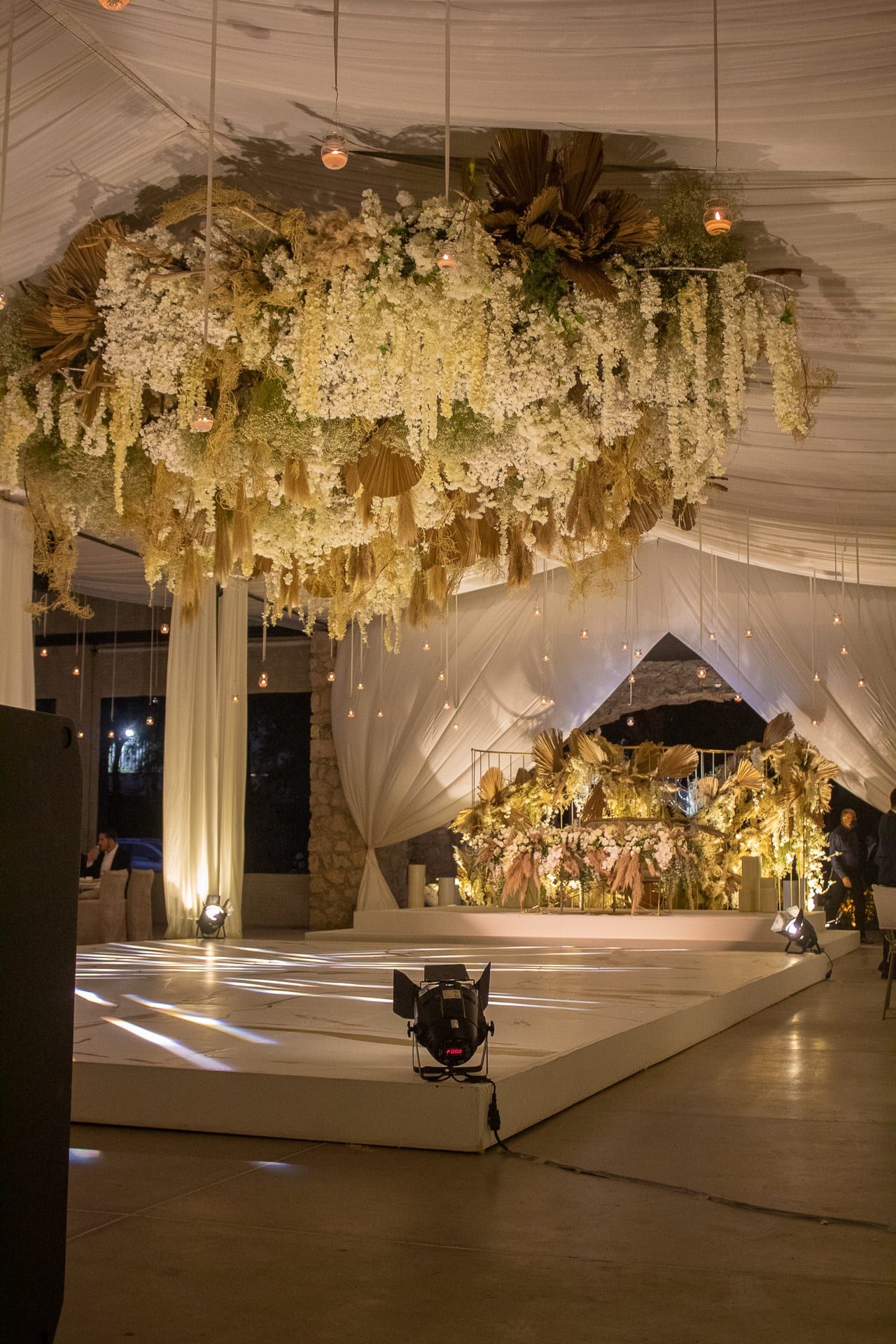 Techo floral colgante sobre la pista, con cortinas de tela blanca