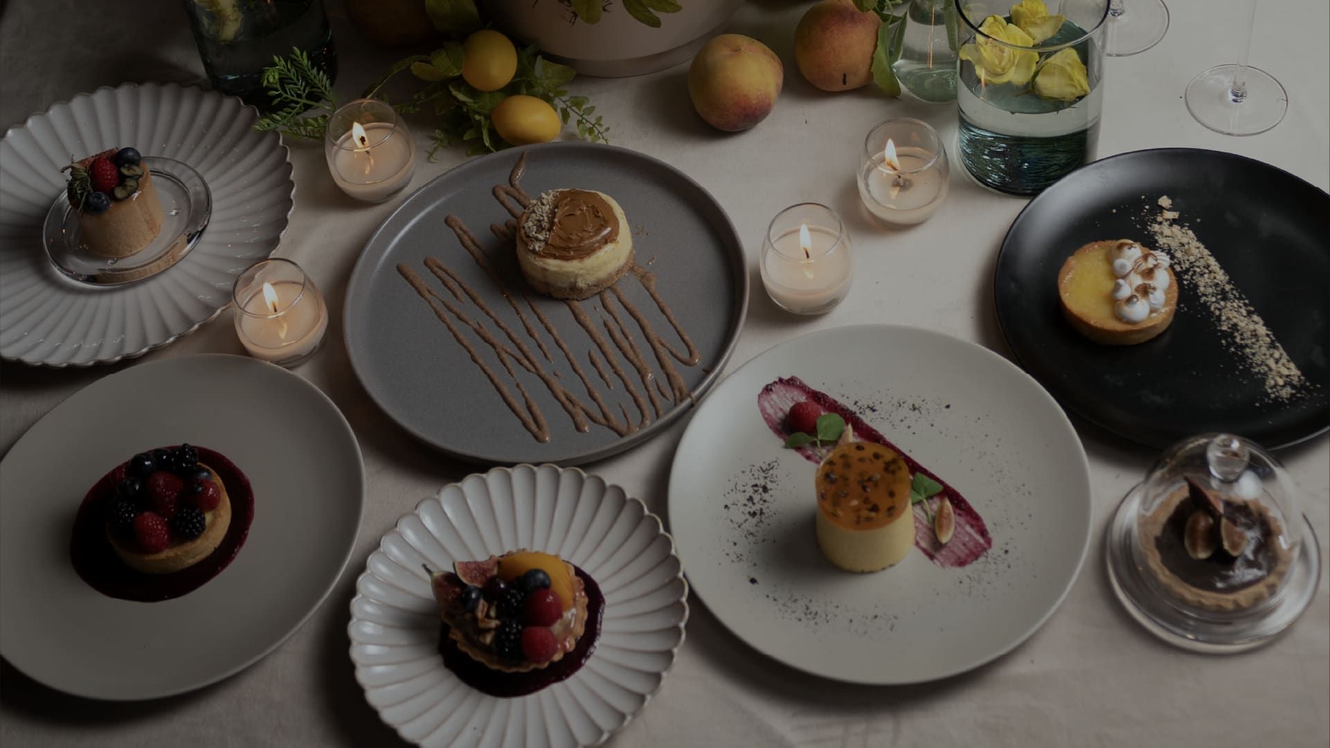 Mesa vista desde arriba con platos de postres individuales, velas pequeñas y frutas