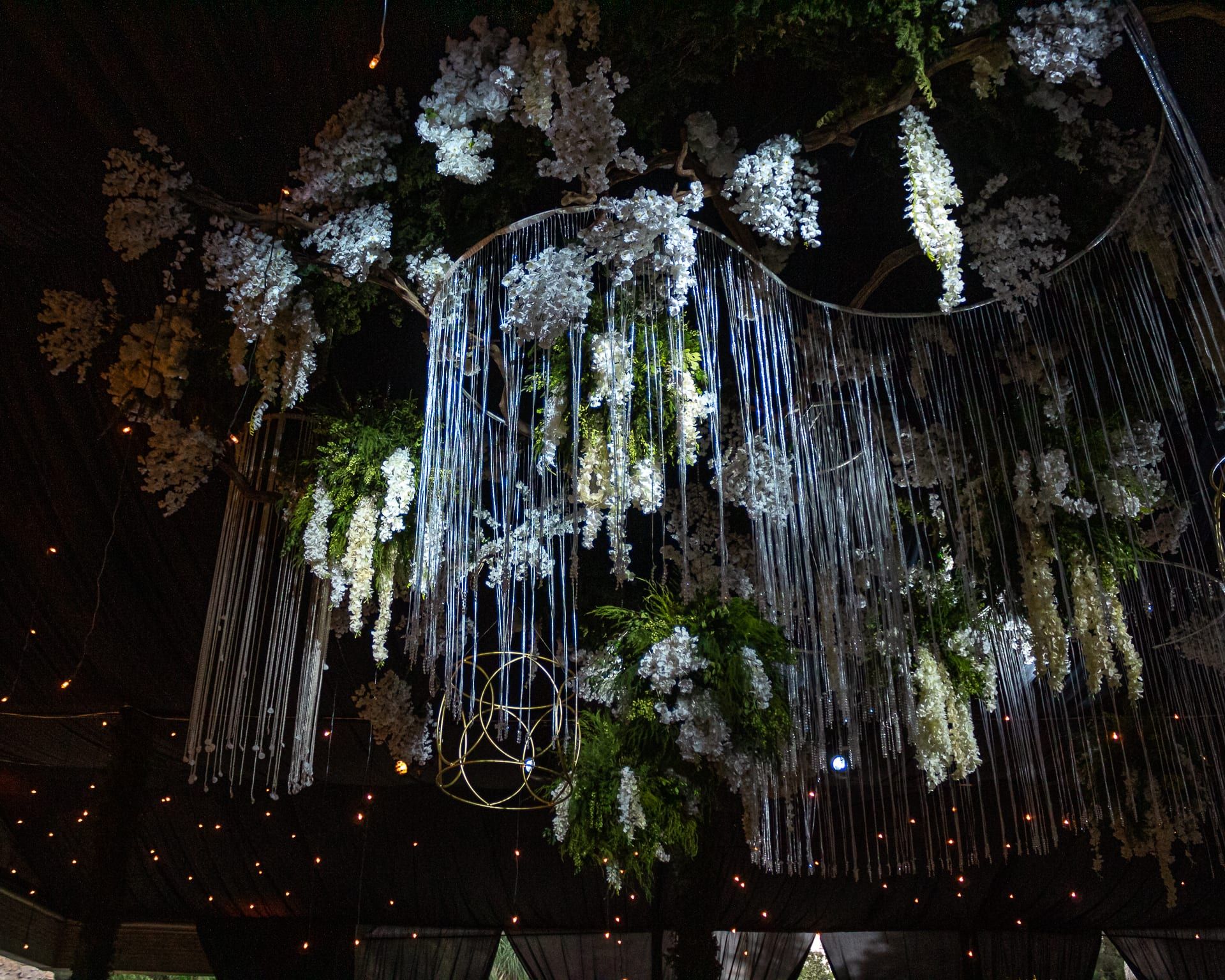 Instalación de flores blancas y cuentas de cristal colgantes sobre el salón oscuro